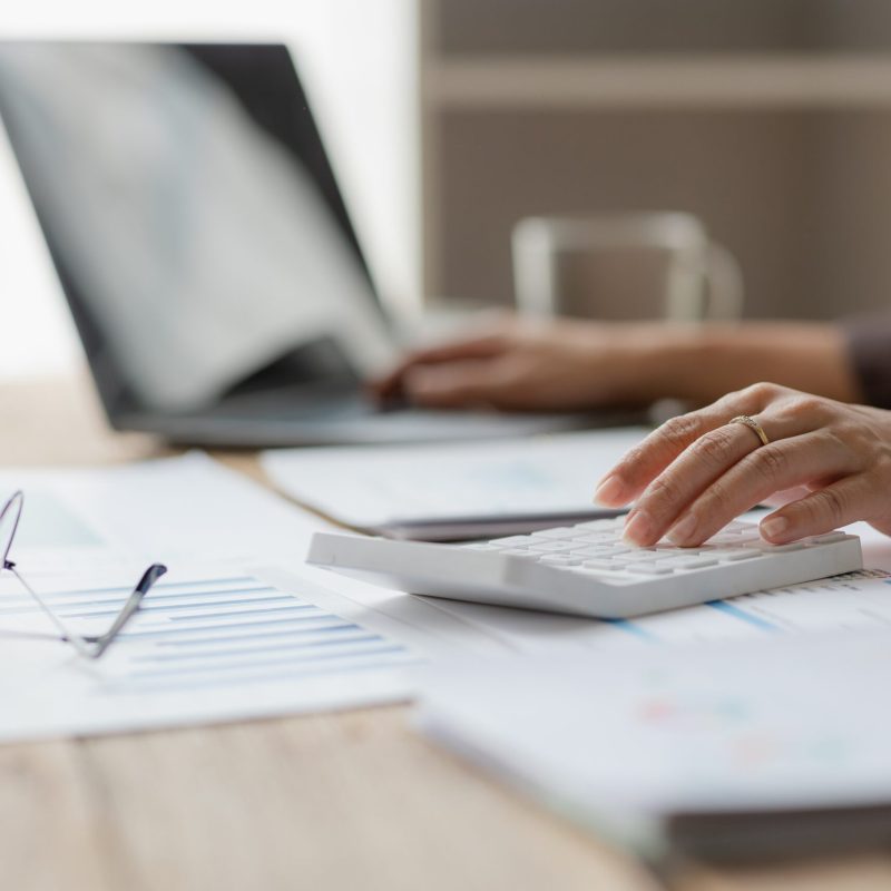 Close-up,Shot,Of,Businesswoman,Using,Calculator,And,Laptop,To,Calculate
